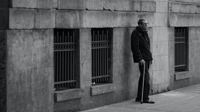 man standing with a cane in a city